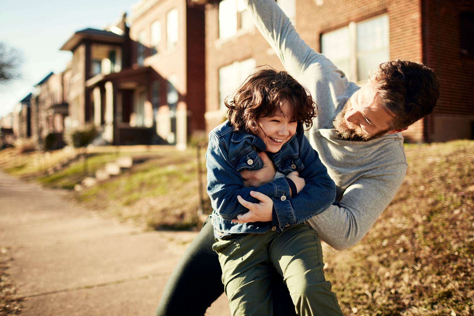 An adult and a child are playing together on a sunny sidewalk in a master-planned community, enjoying quality time in the heart of the welcoming Medina Valley neighborhood.