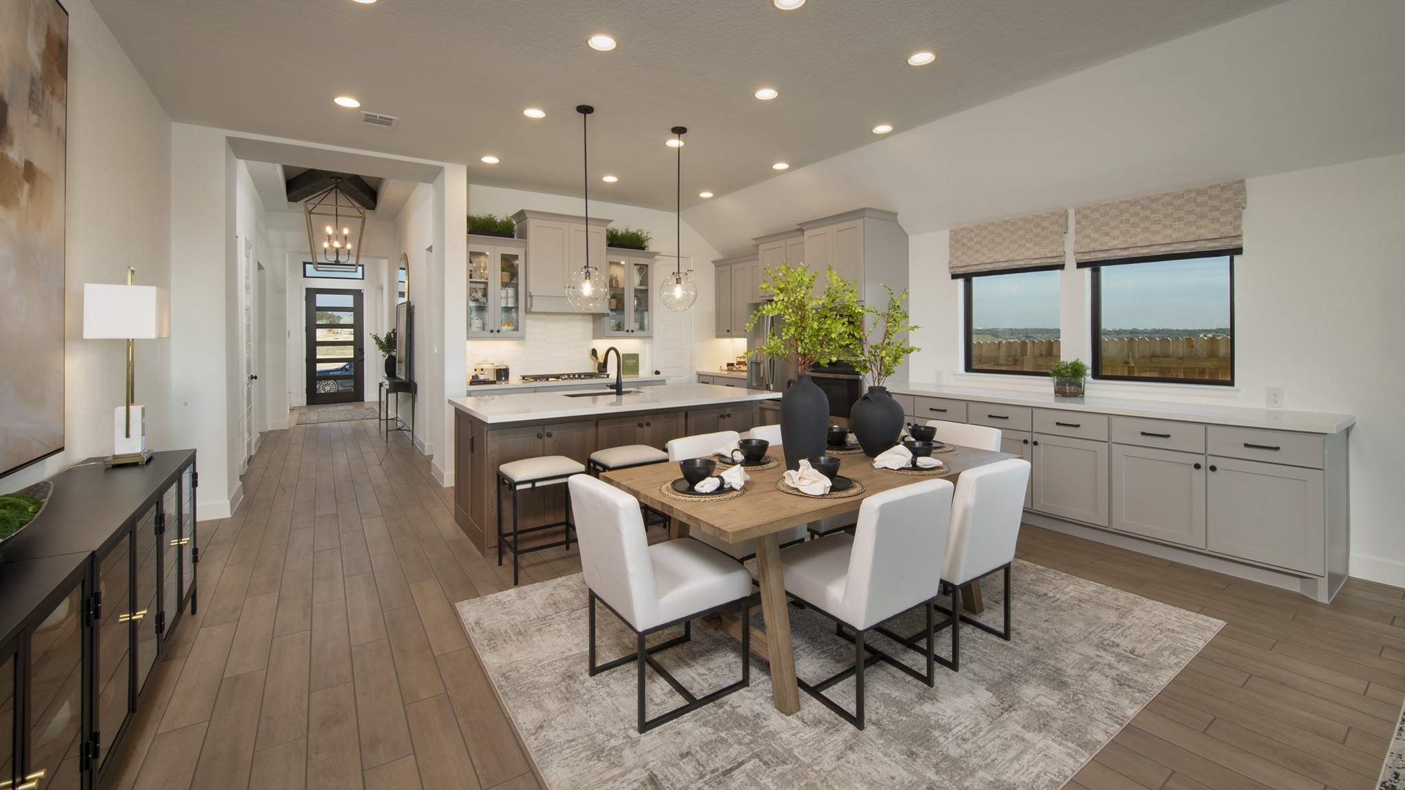 Modern kitchen and dining area with neutral decor, wooden floors, and large windows.