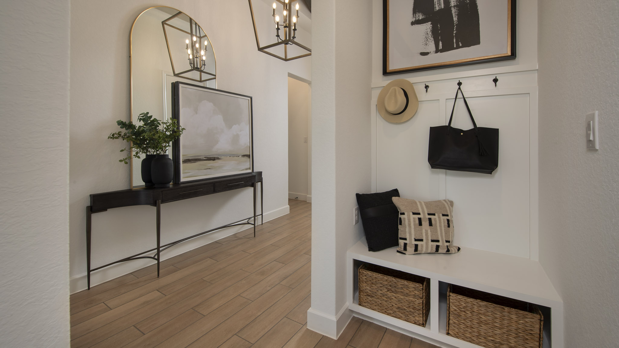 Modern entryway with a bench, baskets, hooks, a mirror, and decorative accents.