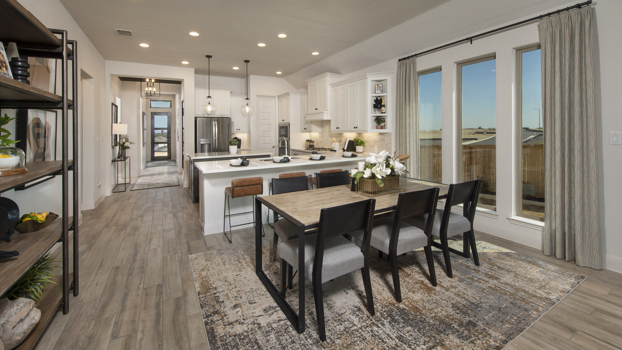 Modern kitchen and dining area with wooden floors, large windows, and neutral decor.