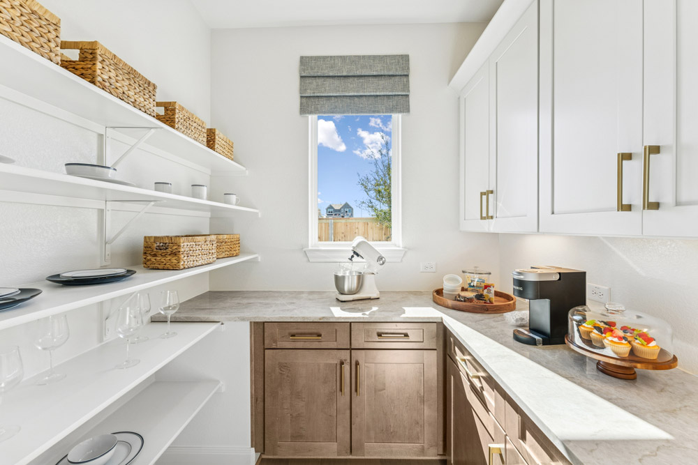 Modern pantry with open shelves, countertop appliances, and a window showing a house outside.