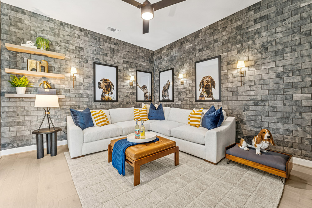 Modern living room with a white sectional, dog-themed art, and a dog sitting on a pet bed.
