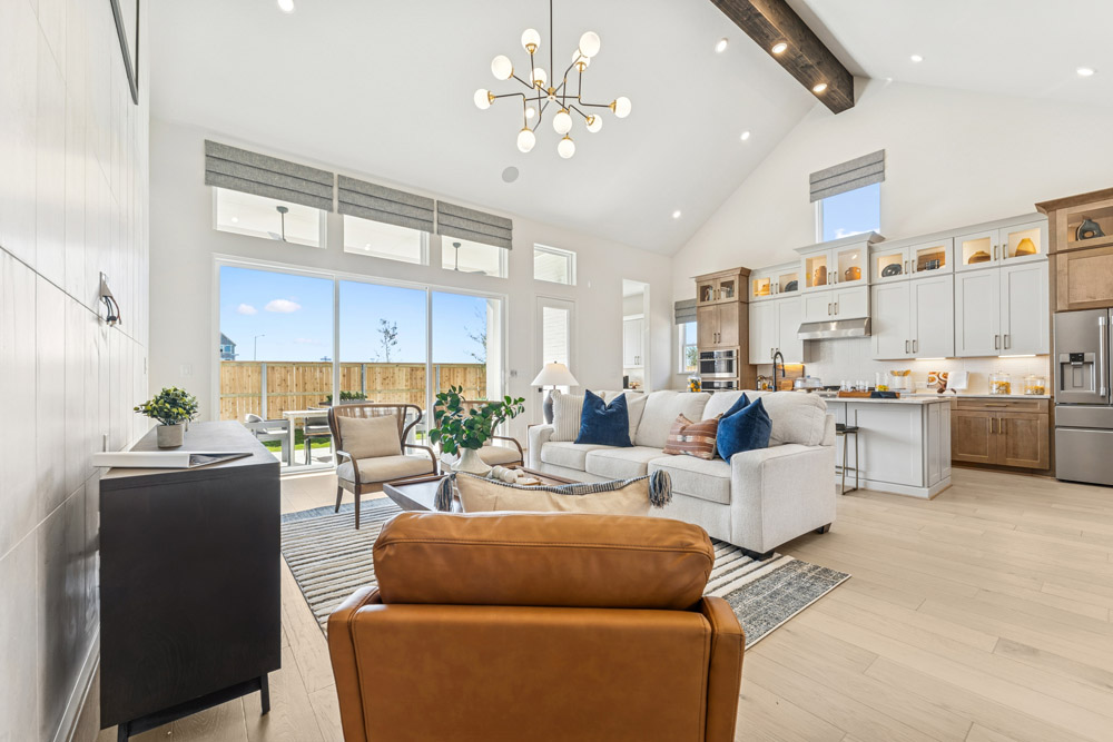 Modern open-concept living room and kitchen with large windows and neutral furnishings.