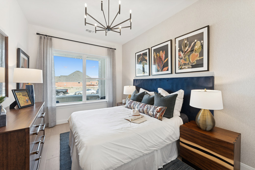 Modern bedroom with a queen bed, large window, and framed art above the headboard.