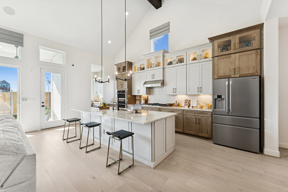 Modern kitchen with white cabinets, island seating, and stainless steel appliances.