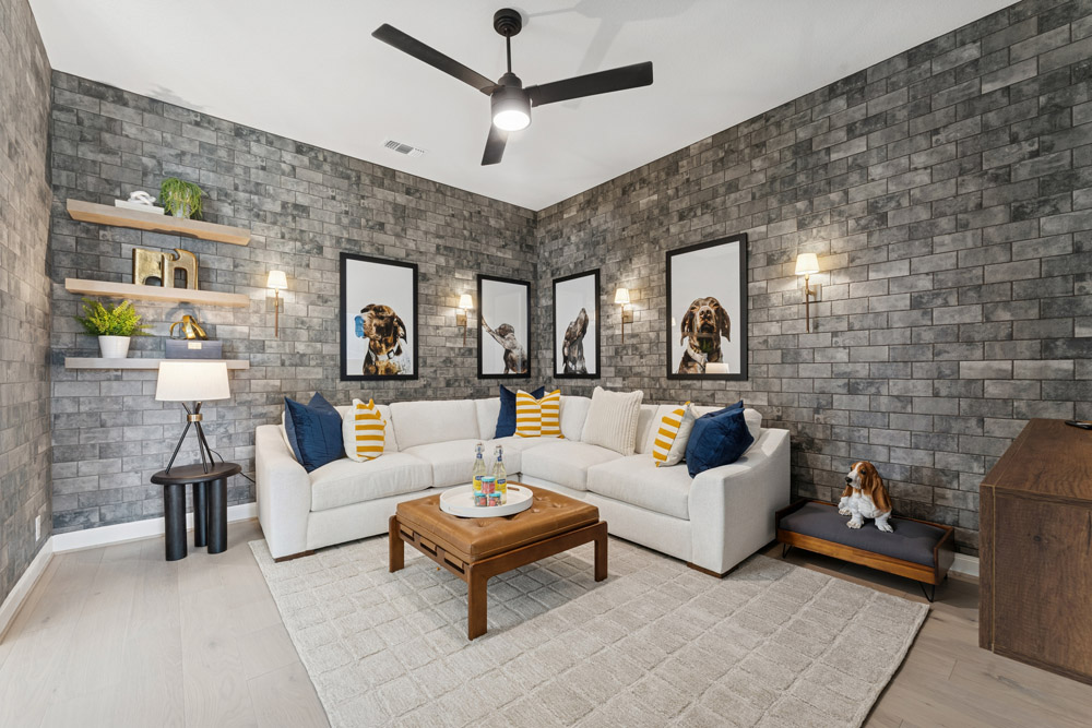 Modern living room with gray brick walls, white sectional sofa, dog art, and wood coffee table.