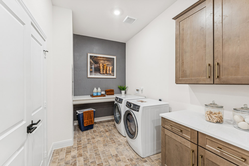 Modern laundry room with washer, dryer, wooden cabinets, and countertop storage jars.