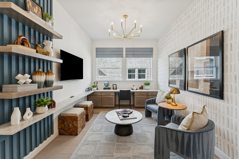 Modern home office with desk, shelves, two chairs, wall art, and large windows.