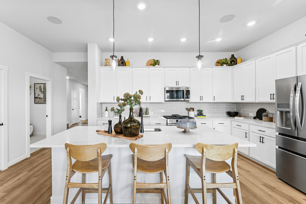 Modern kitchen with white cabinets, stainless steel appliances, and a central island with stools.
