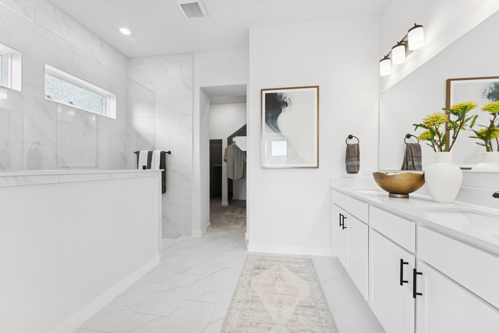 Modern white bathroom with double sinks, large mirror, wall art, and walk-in shower.