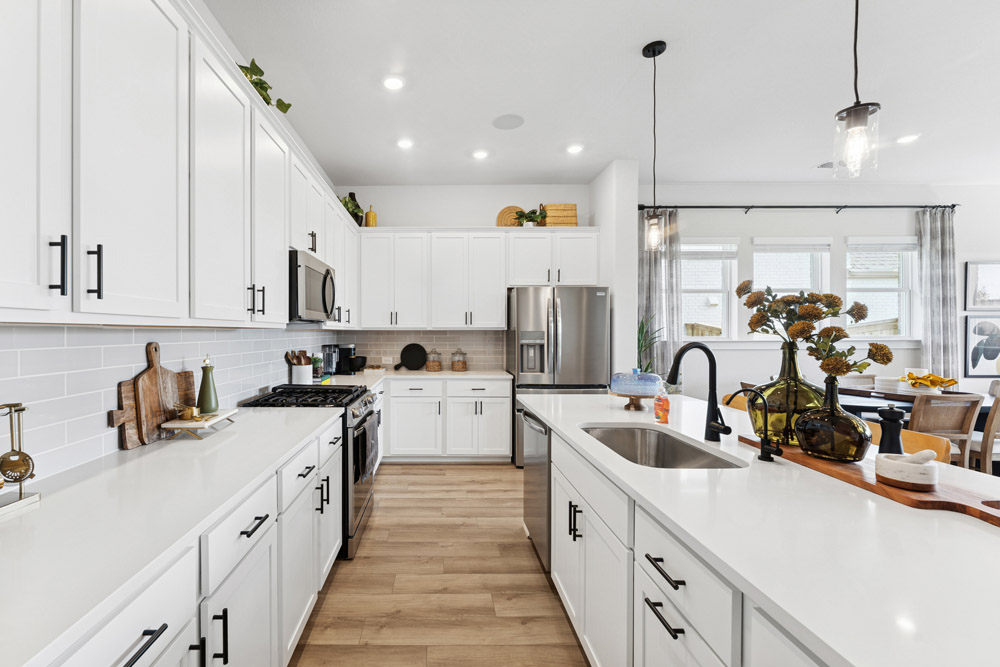 Modern kitchen with white cabinets, stainless steel appliances, and a center island sink.