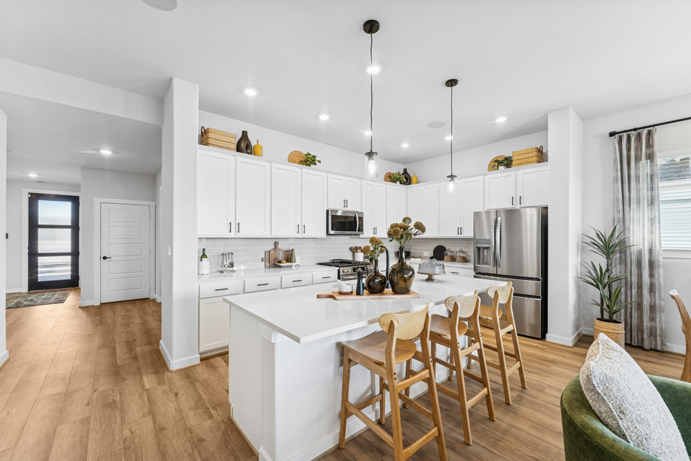 Modern kitchen with white cabinets, island seating, and stainless steel appliances.