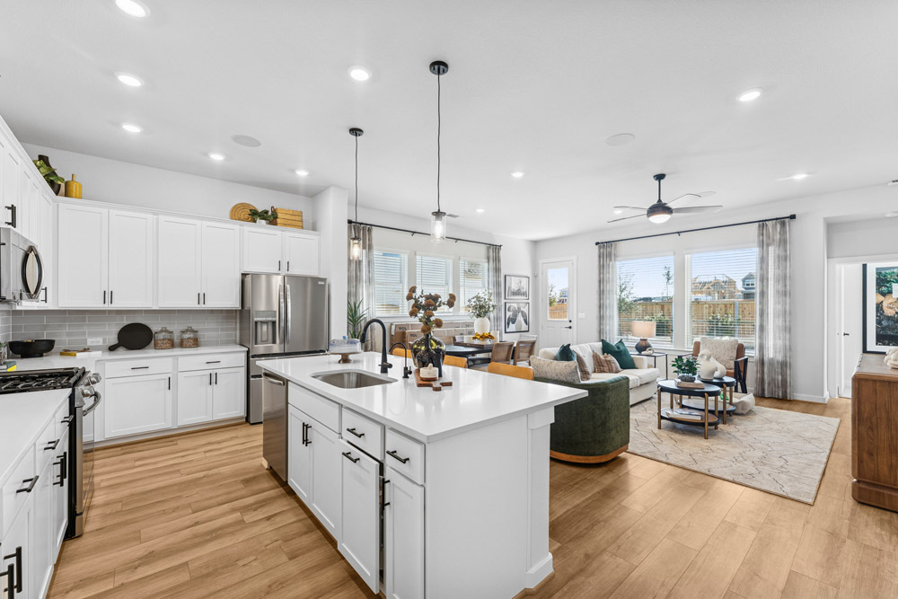 Modern open-concept kitchen and living room with white cabinets, island, and wood floors.