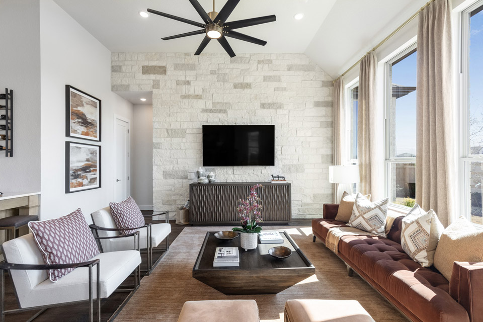 Modern living room with large windows, stone accent wall, and contemporary furnishings.