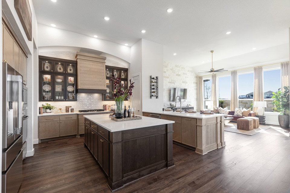 Modern kitchen with dark wood floors, island, and open view to a bright living area.