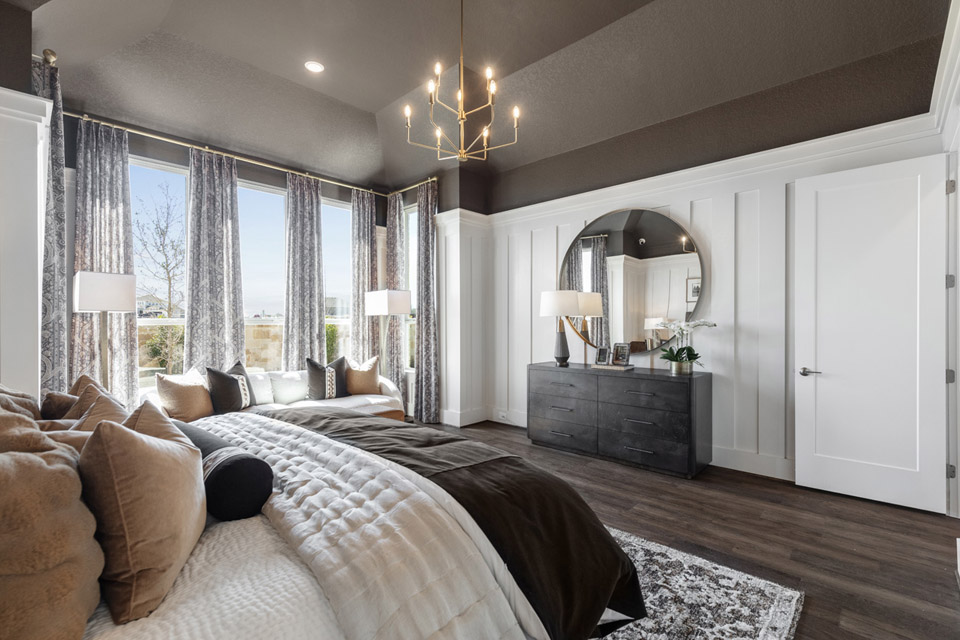 Modern bedroom with large windows, a round mirror, black dresser, and neutral decor.