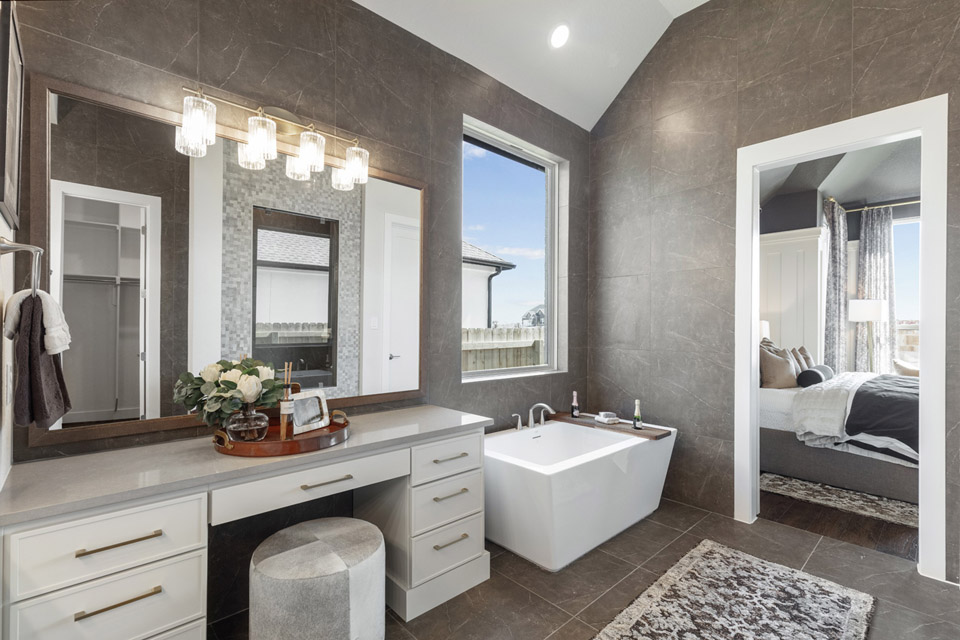 Modern bathroom with a large vanity, freestanding tub, and entryway to a bedroom.