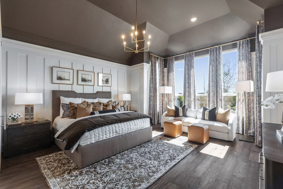 Modern bedroom with large bed, seating area by window, and neutral-colored decor.