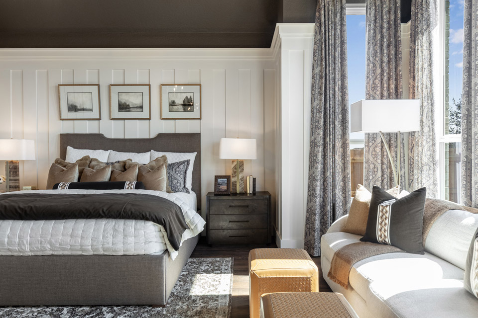 Modern bedroom with a large bed, nightstands, couch, lamps, and sunlight streaming in.