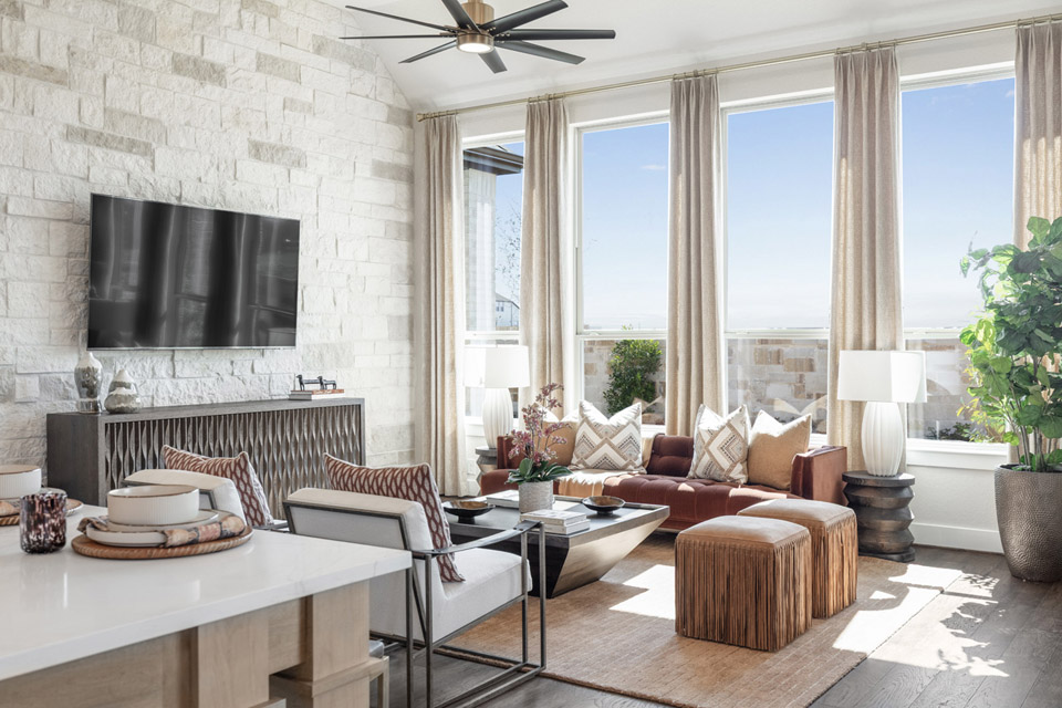 Bright modern living room with large windows, neutral decor, a TV, and contemporary furnishings.