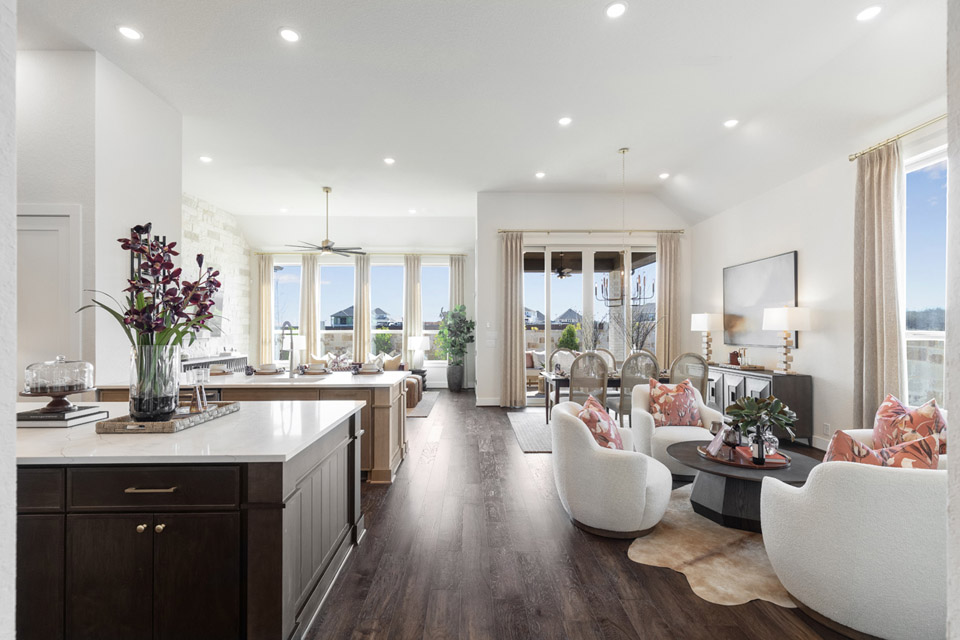 Modern open-plan living room and kitchen with large windows, neutral tones, and contemporary furniture.